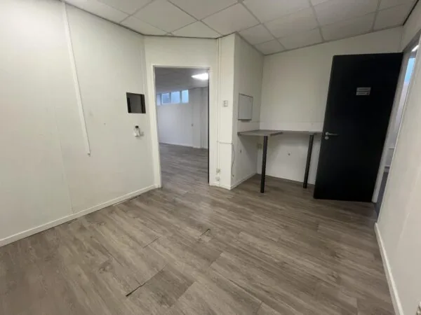 Lege kantoorruimte aan de Burgemeester Smitsstraat met laminaatvloer, witte muren en een zwarte deur.